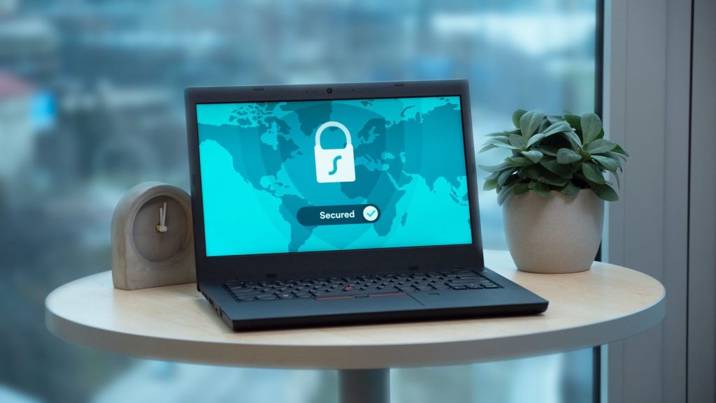 Laptop on a small round table showing a padlock icon and the word secured